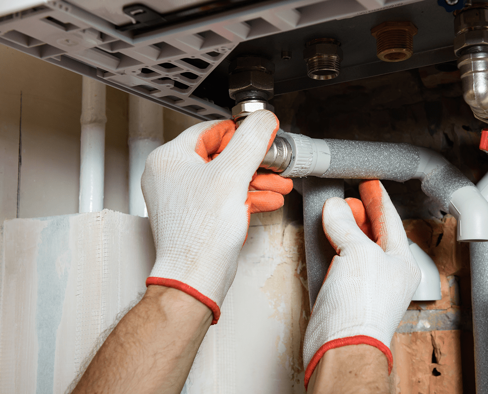 Técnico ajustando conexión hidráulica con guantes de protección en una instalación de fontanería